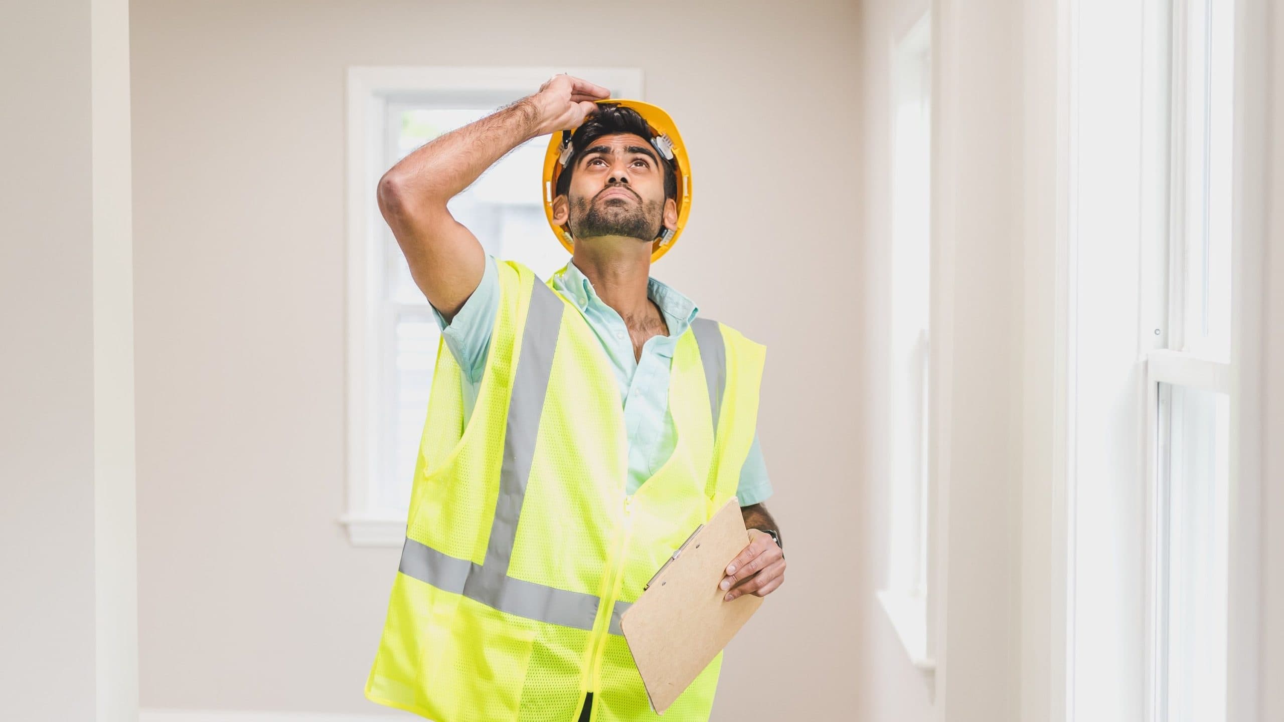 Home inspection in a reflective vest looking at the ceiling